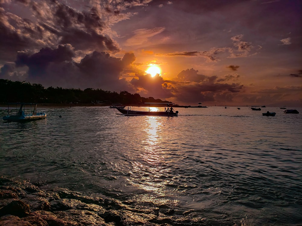 a sunset over the ocean with boats in the water