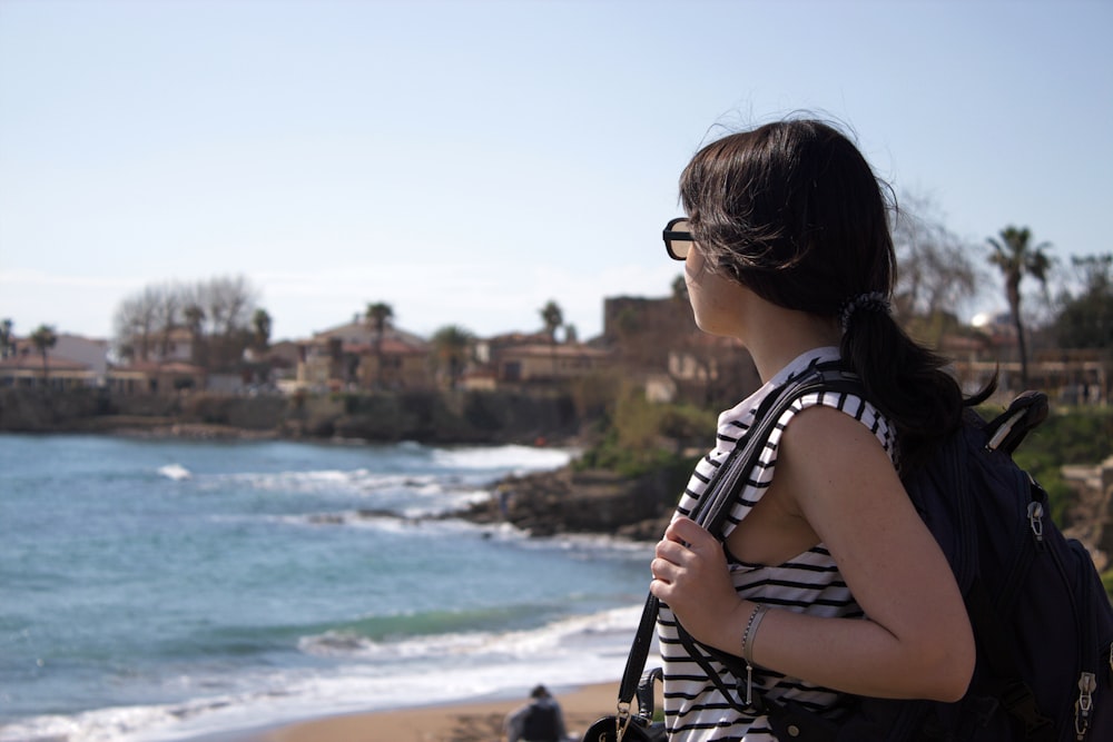 a woman standing on a beach looking at the ocean