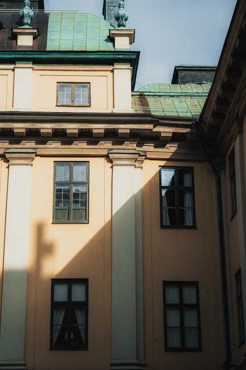 An old yellow building with white columns and a green roof