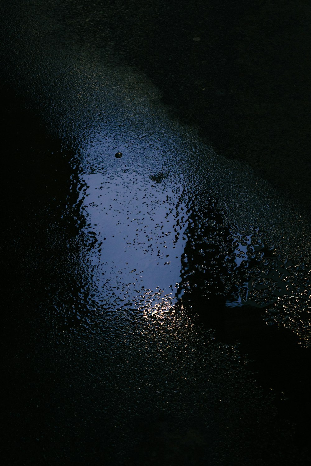 a street light reflecting off of a puddle of water