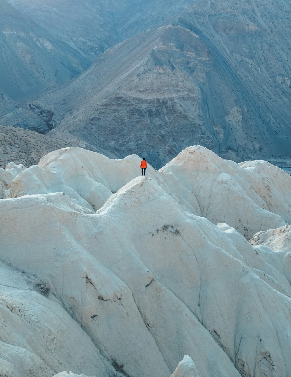 uma pessoa em pé no topo de uma montanha branca