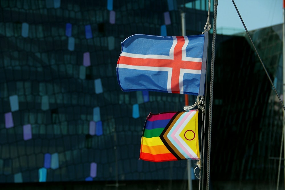two flags hanging from a pole in front of a building