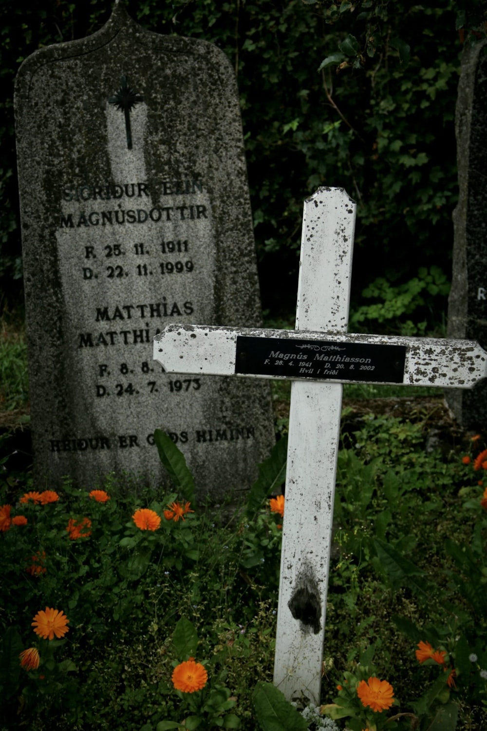 a cemetery with two headstones and flowers in the foreground