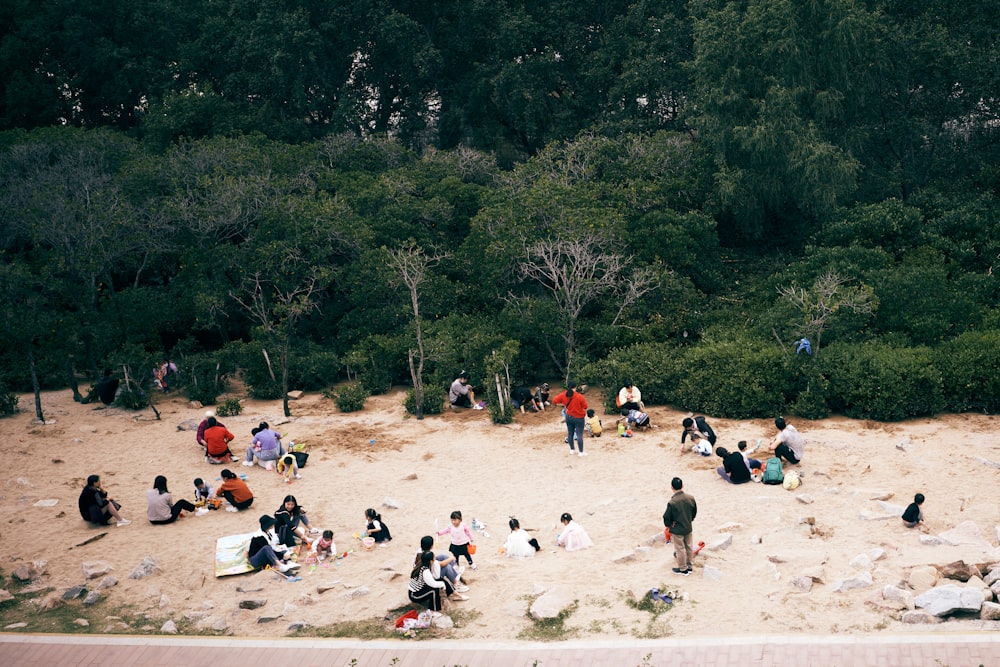 a group of people sitting on top of a sandy beach