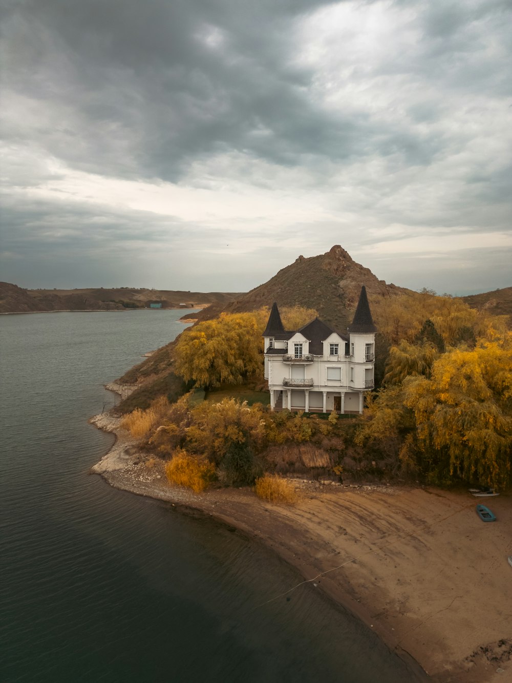 a large white house sitting on top of a hill next to a body of water