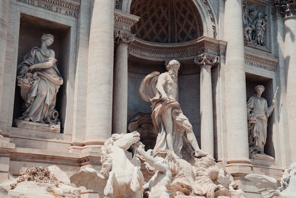 a close up of a fountain with statues around it