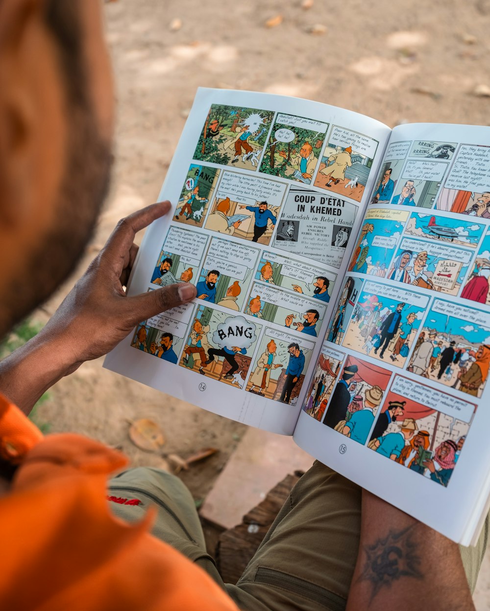 a man is reading a comic book outside