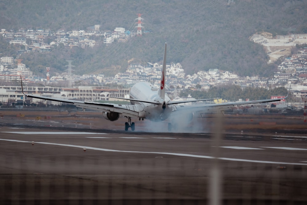 a plane on a runway with a city in the background