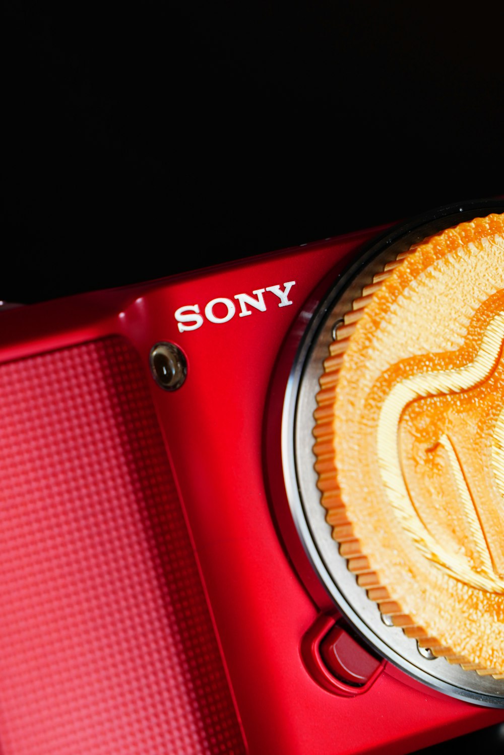 Una fotocamera Sony rossa con un biscotto sopra