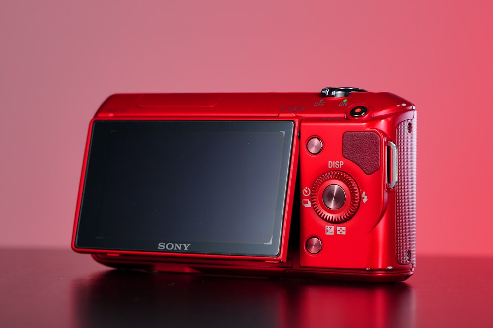 a red digital camera sitting on top of a table