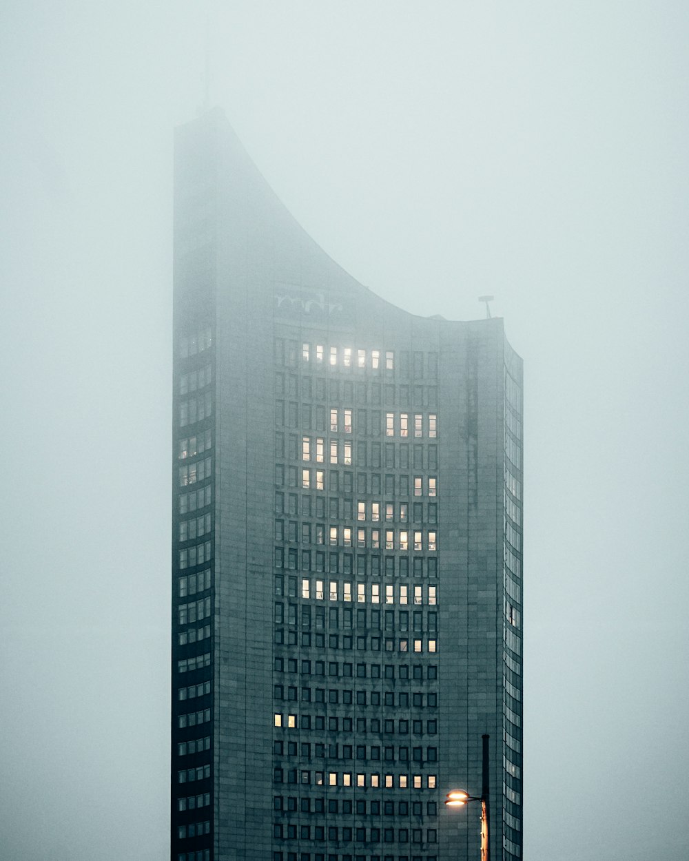 a very tall building in the middle of a foggy day