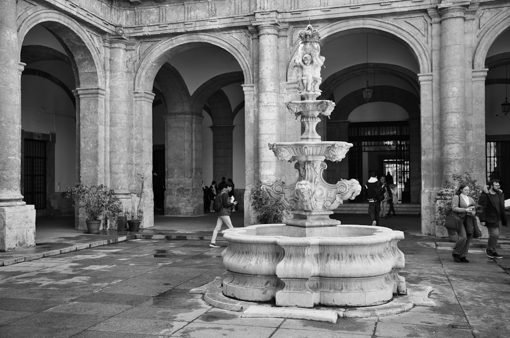 a black and white photo of a fountain in a courtyard