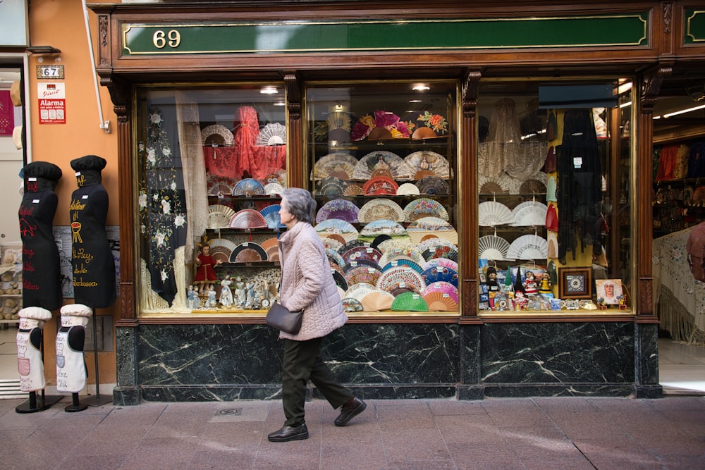 a woman walking past a store front with umbrellas