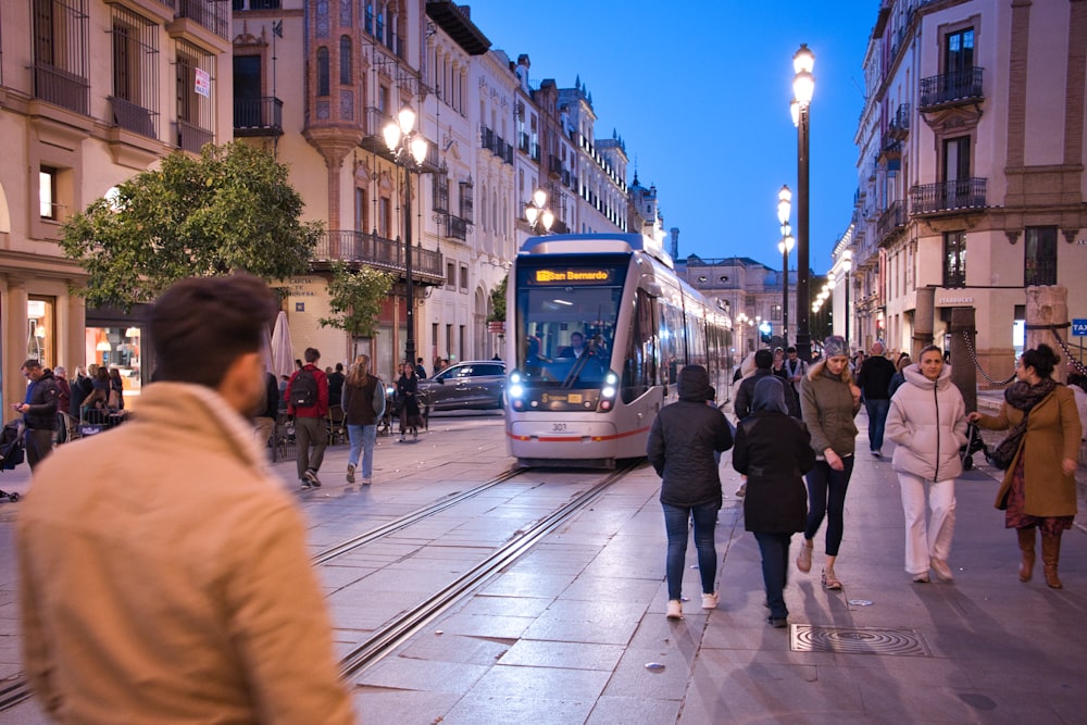 a group of people walking down a street next to a train