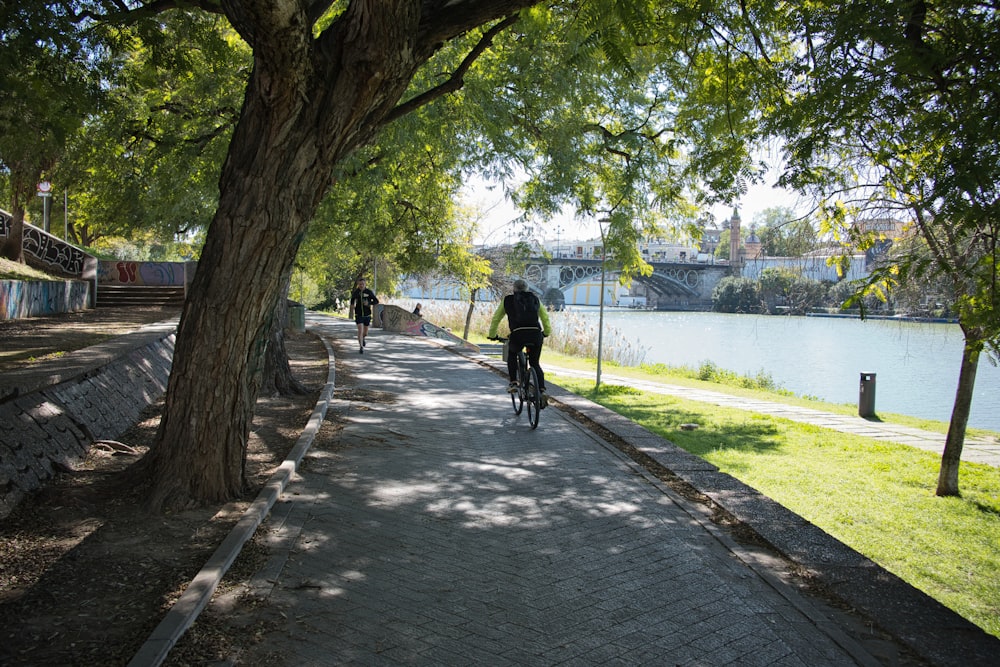 a man riding a bike down a sidewalk next to a river