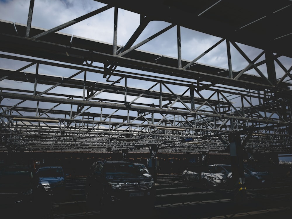 a group of cars parked under a metal structure