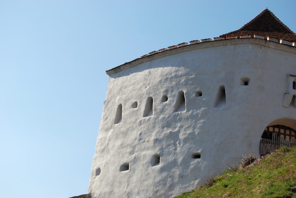 a white building with a brown roof on a hill