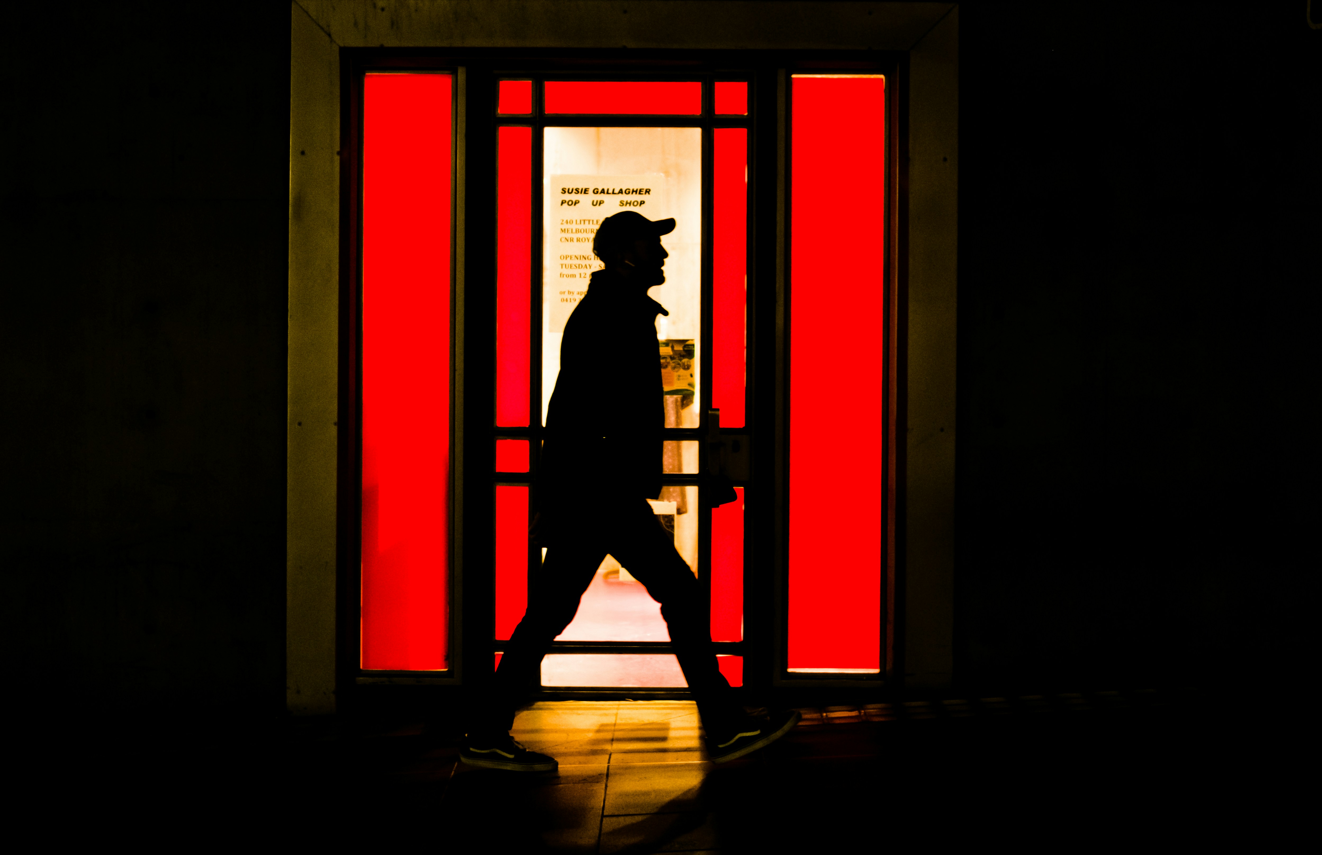 a silhouette of a man walking past a red door