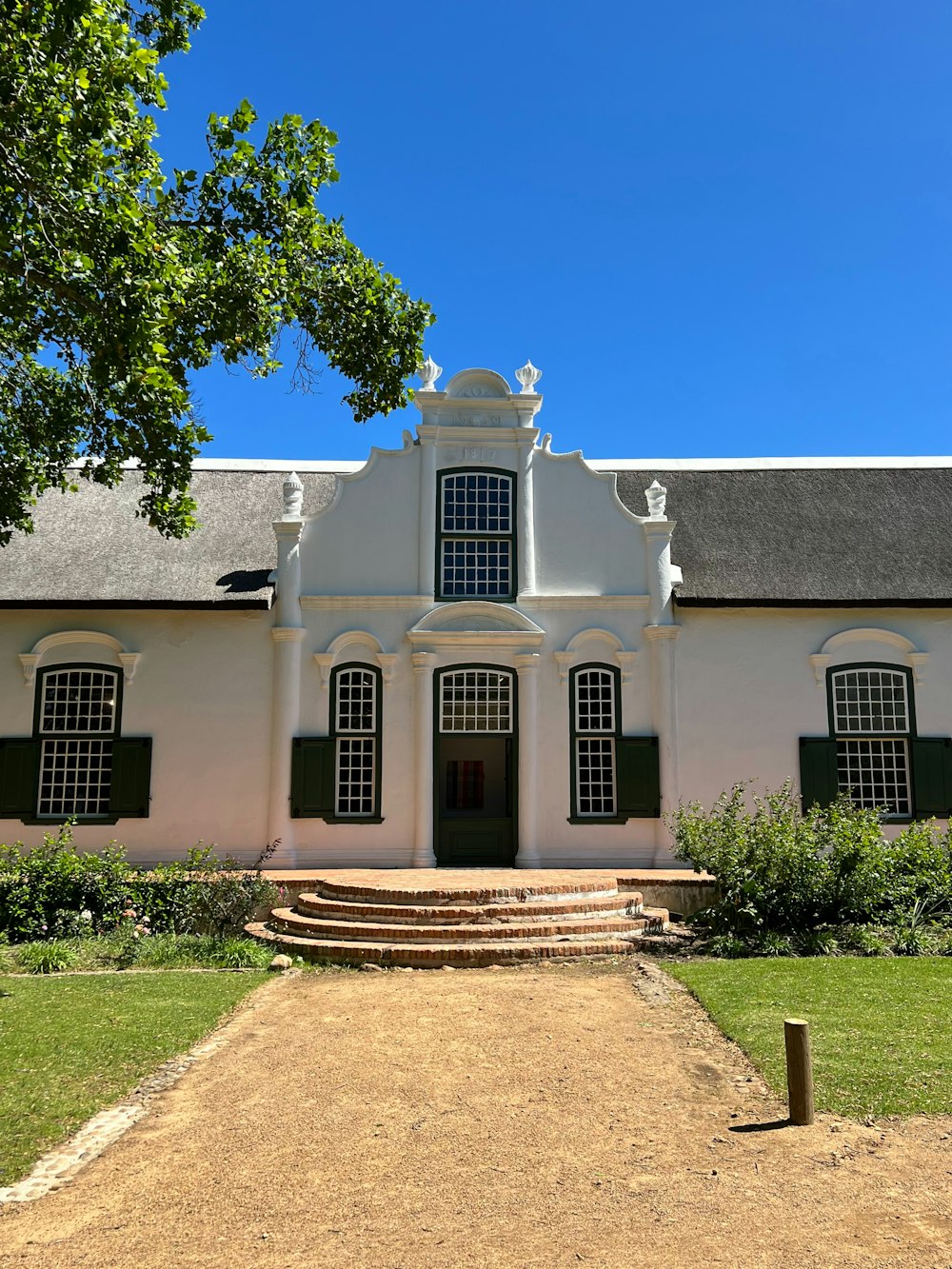 a large white building with green shutters on a sunny day