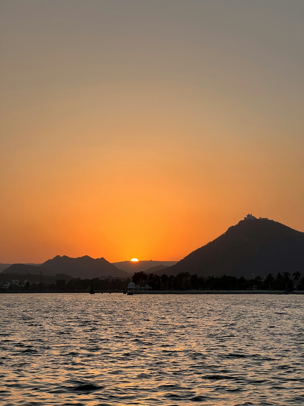 a sunset over a body of water with mountains in the background