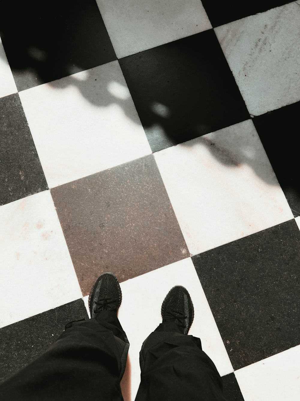 una persona in piedi su un pavimento a scacchi in bianco e nero