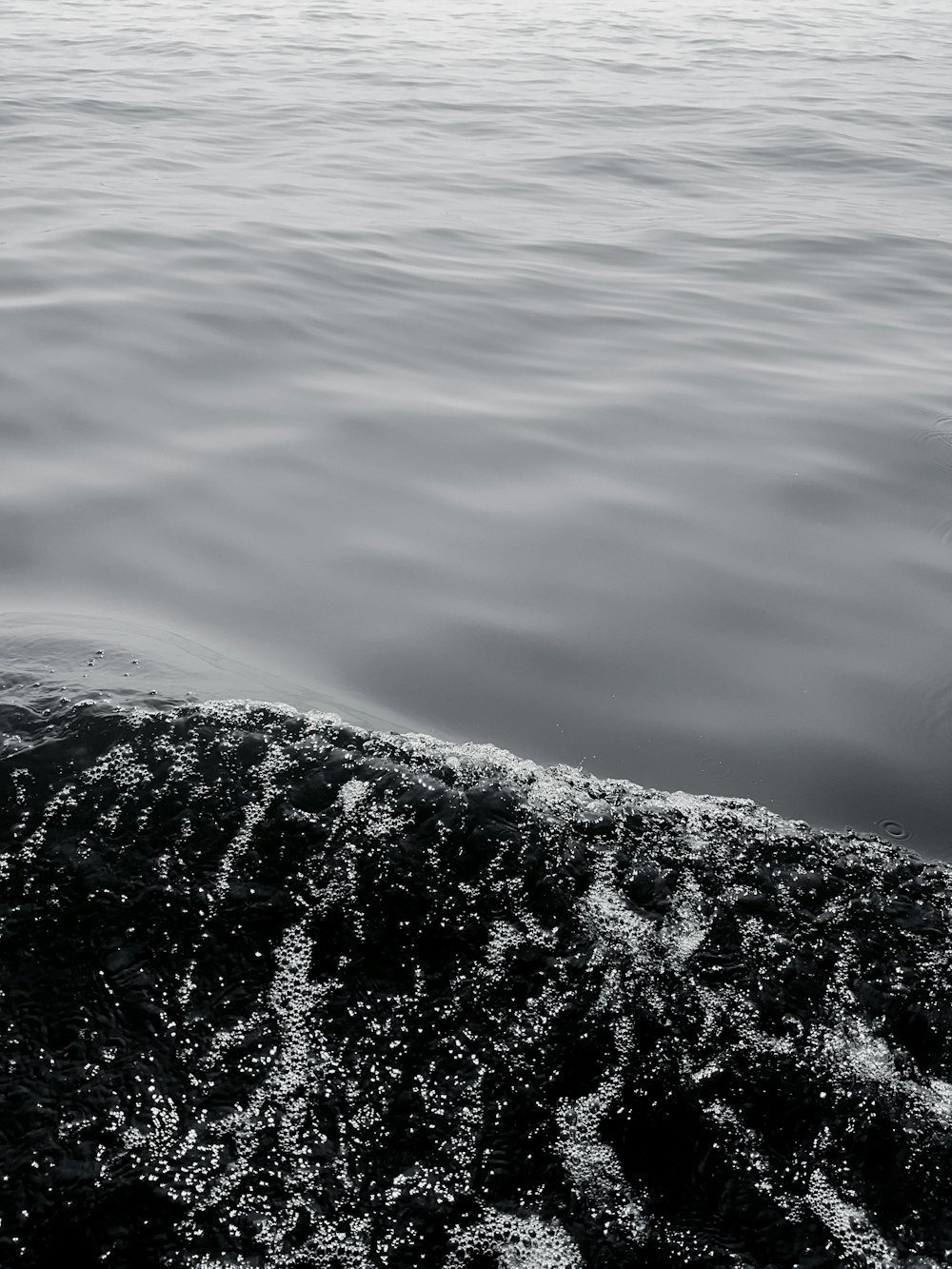 a black and white photo of a wave in the water