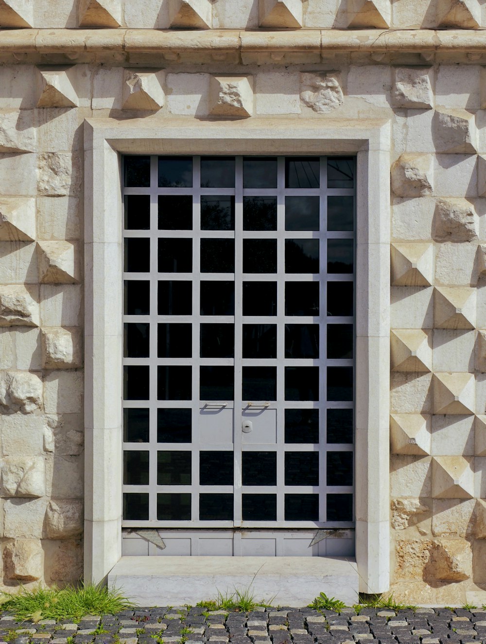 a stone building with a window and a brick sidewalk