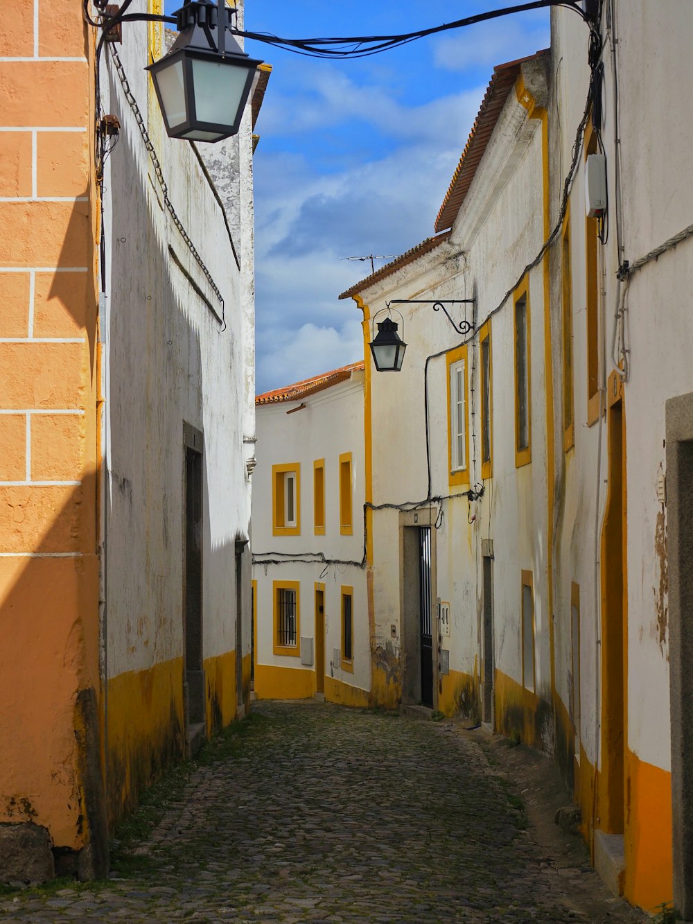 a narrow alley way with a lamp on the side