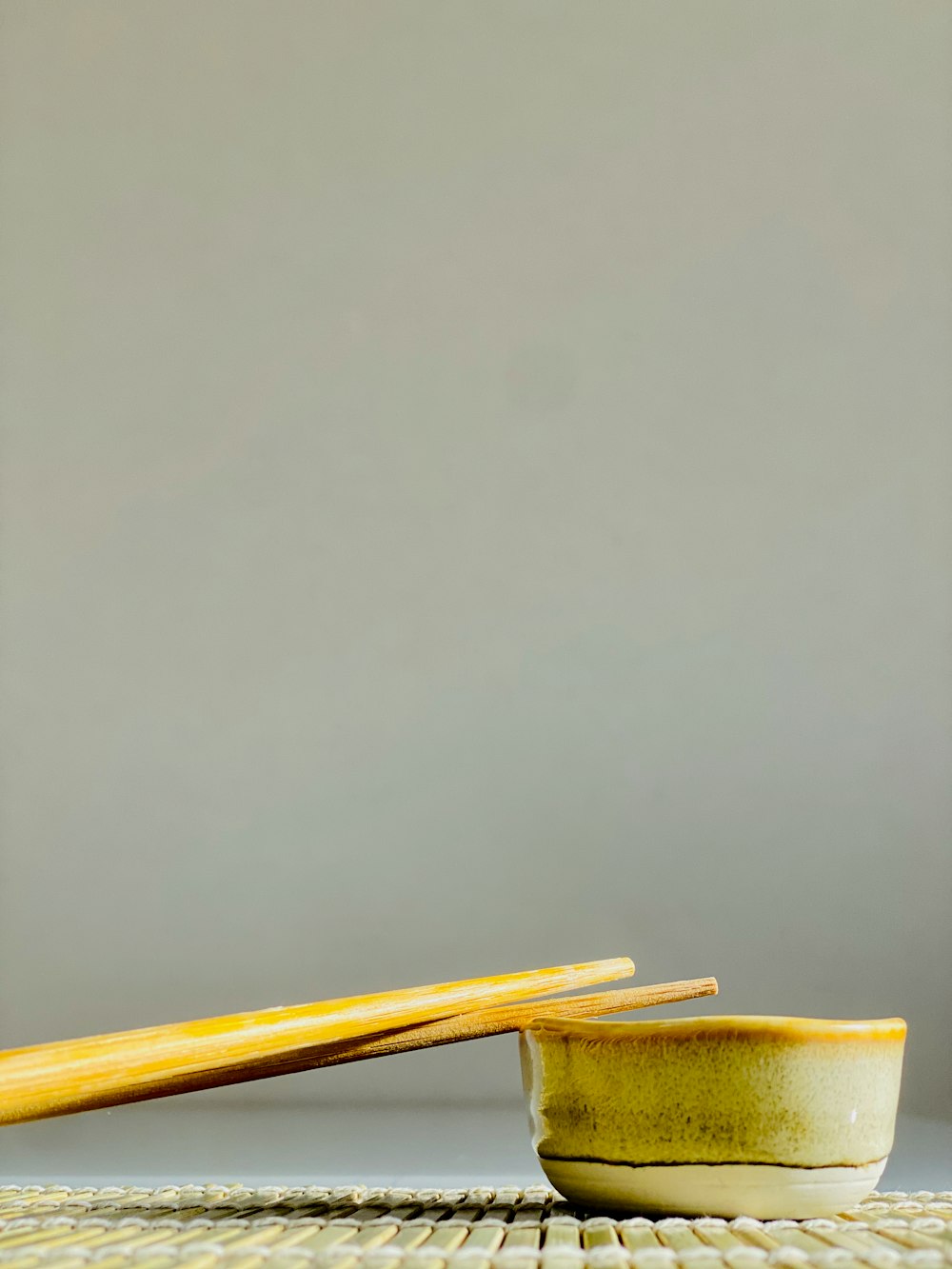 a yellow bowl and chopsticks on a table