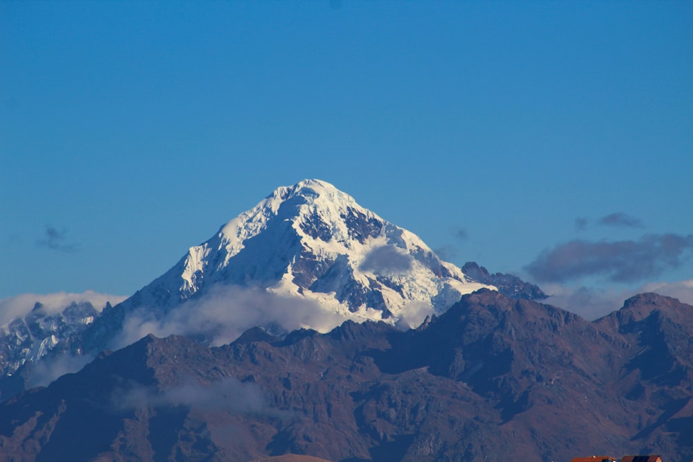 a snow covered mountain in the middle of a blue sky