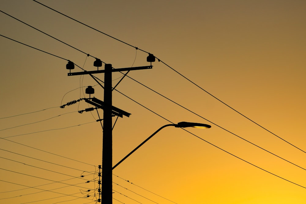 the sun is setting behind power lines and telephone poles