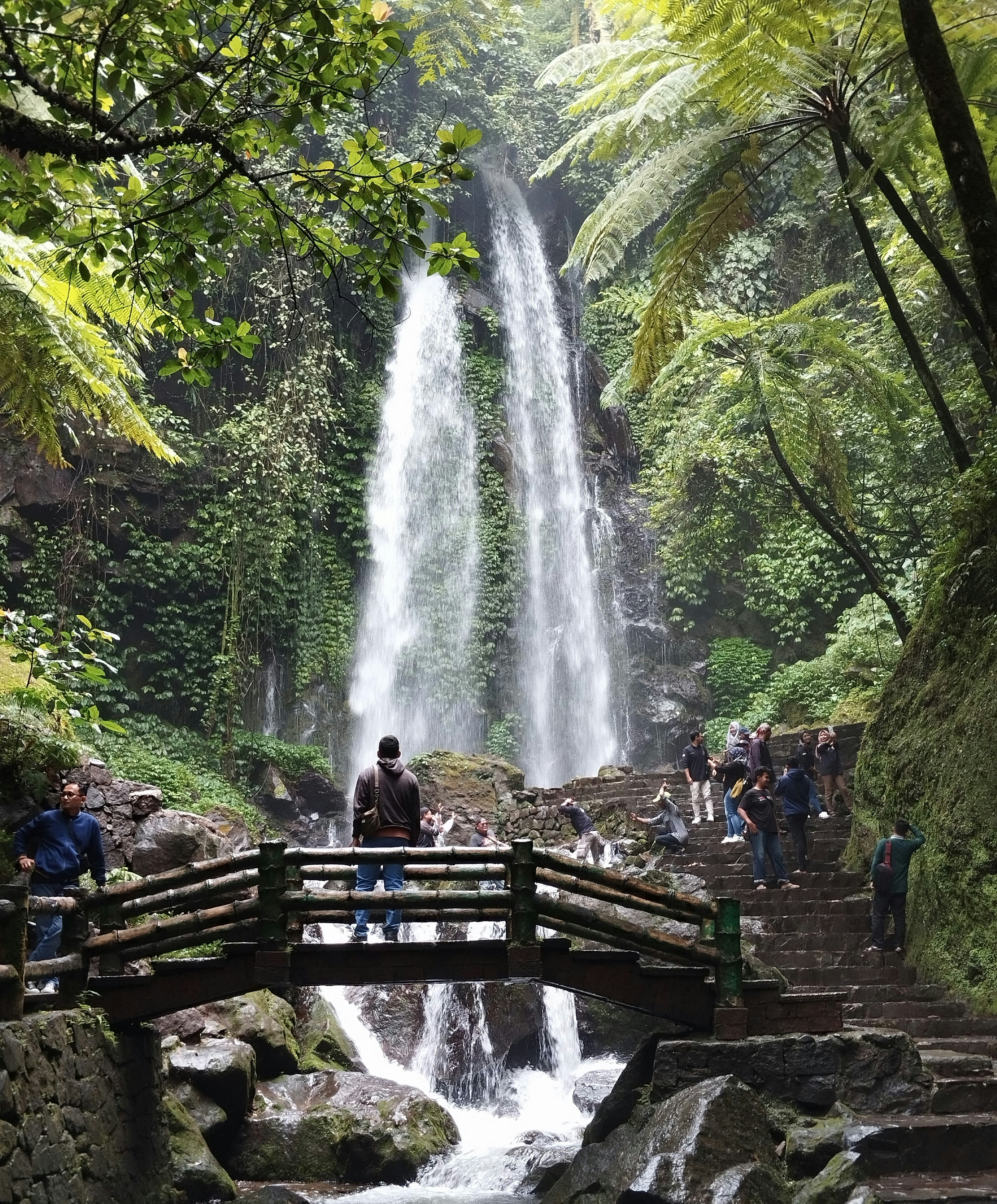 sekelompok orang berdiri di depan air terjun
