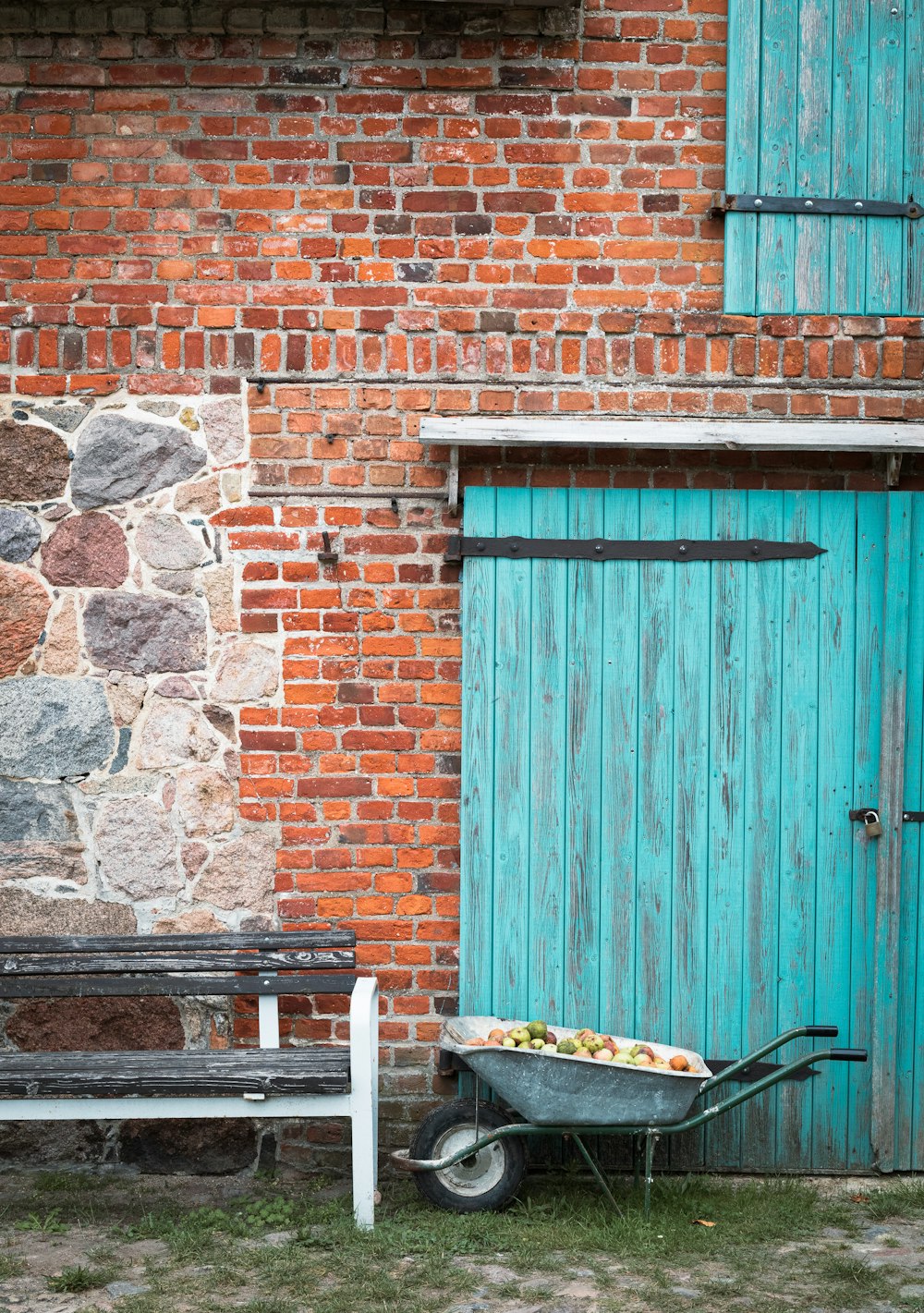 a wheelbarrow next to a brick building with a blue door