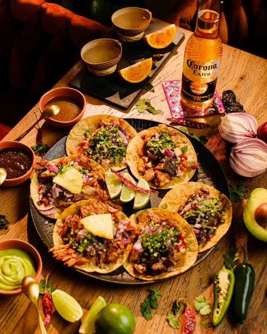 a table topped with tacos and a bottle of beer
