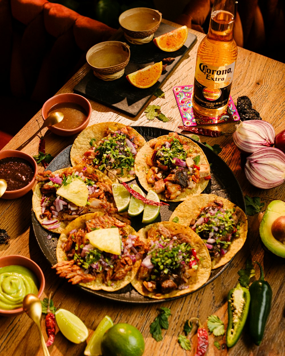 a table topped with tacos and a bottle of beer