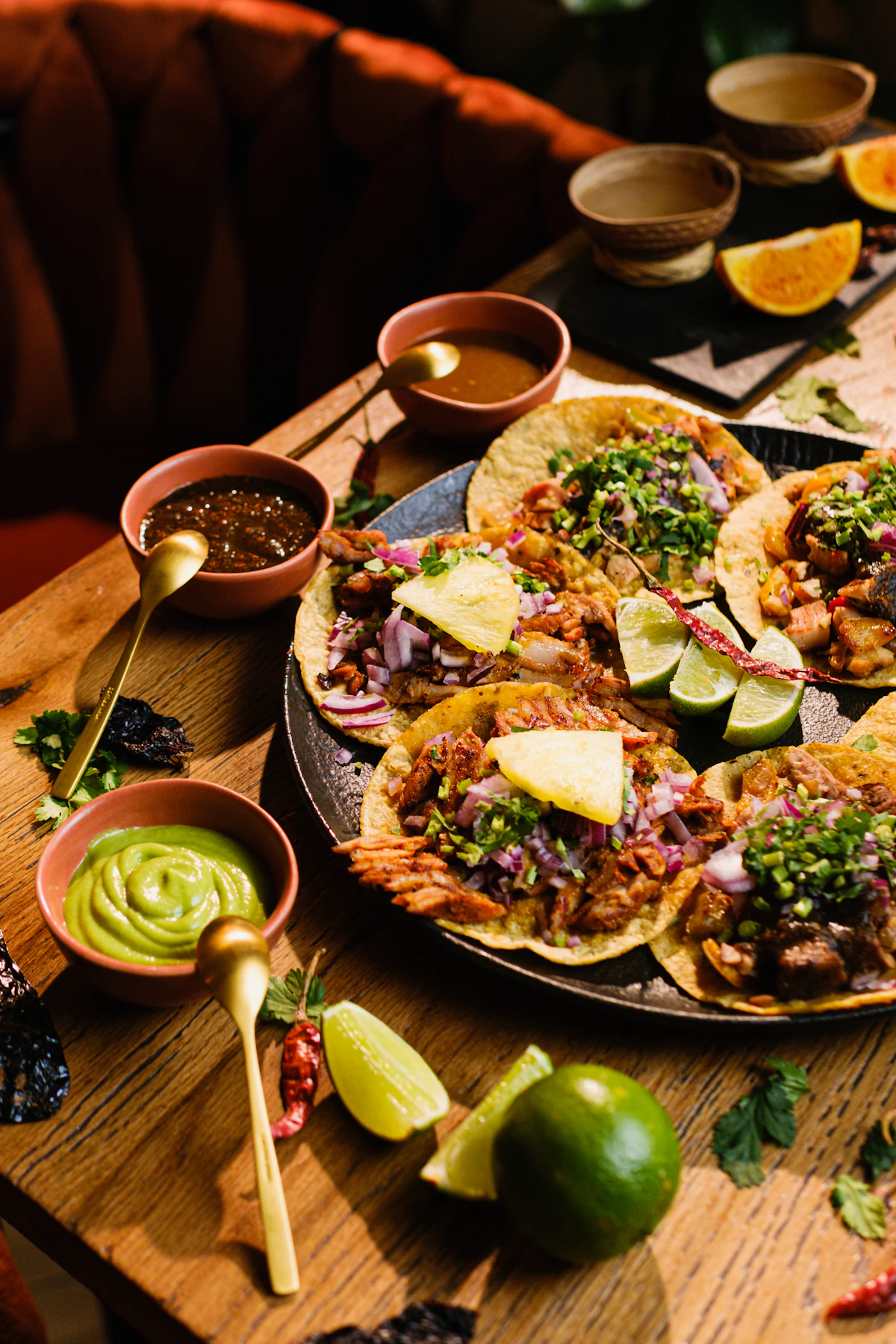 A table set with plates of food and small bowls of red and green salsa