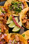 a plate of tacos with limes, onions, and meat