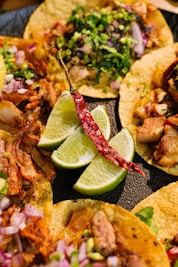 a plate of tacos with limes, onions, and meat