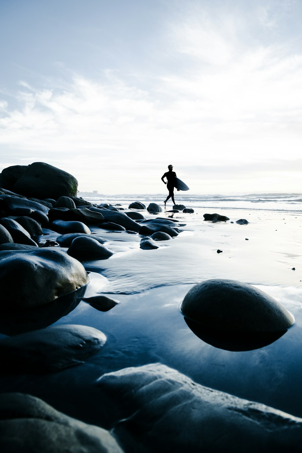 서핑 보드를 가진 사람이 해변을 걷고 있습니다.