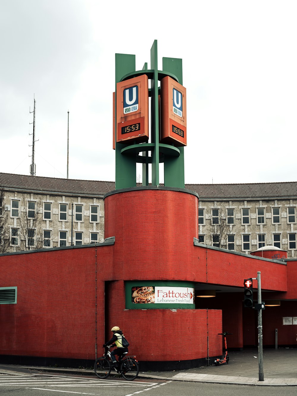 a man riding a bike past a tall red building