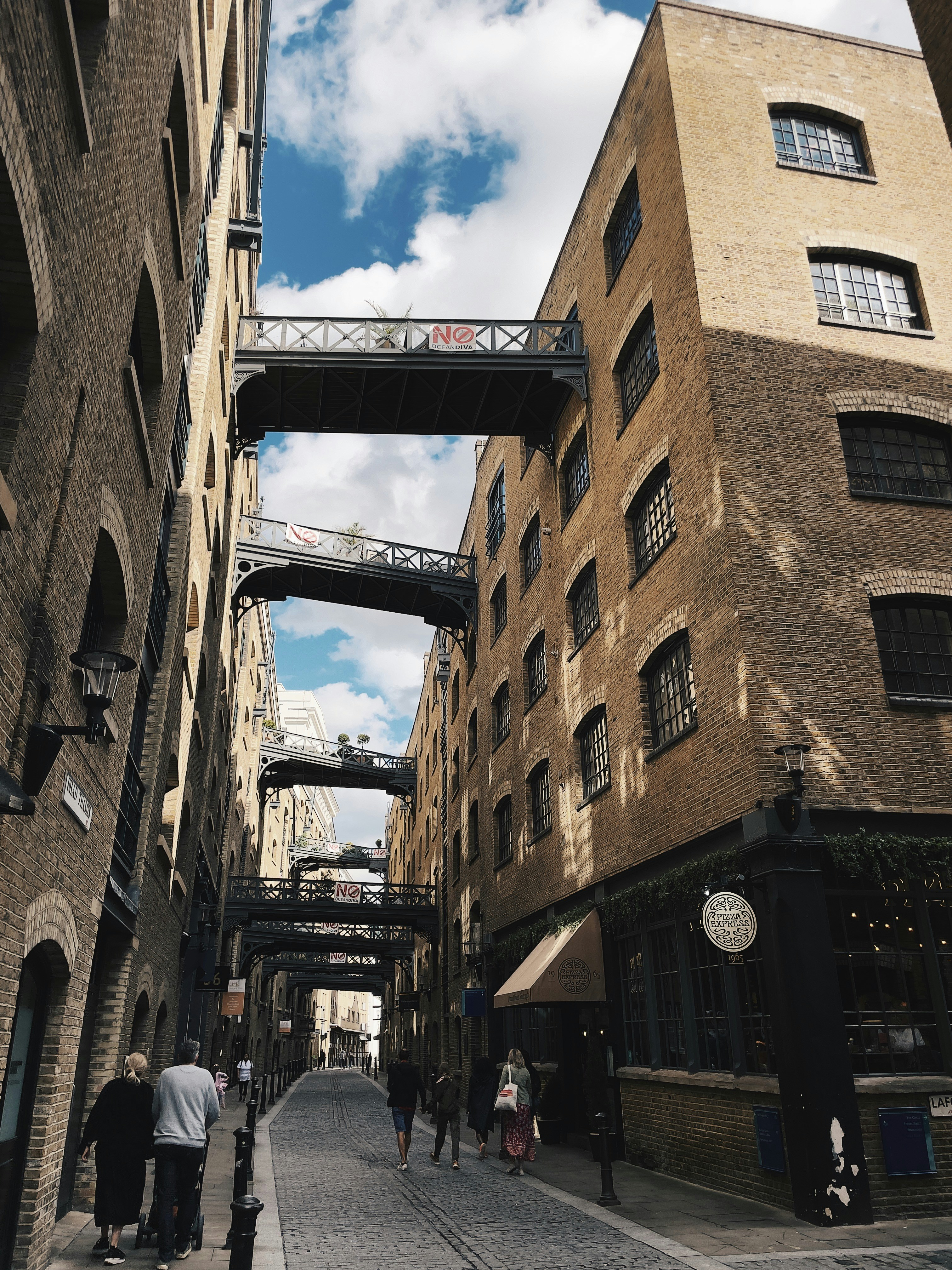 people walking down a street under a bridge