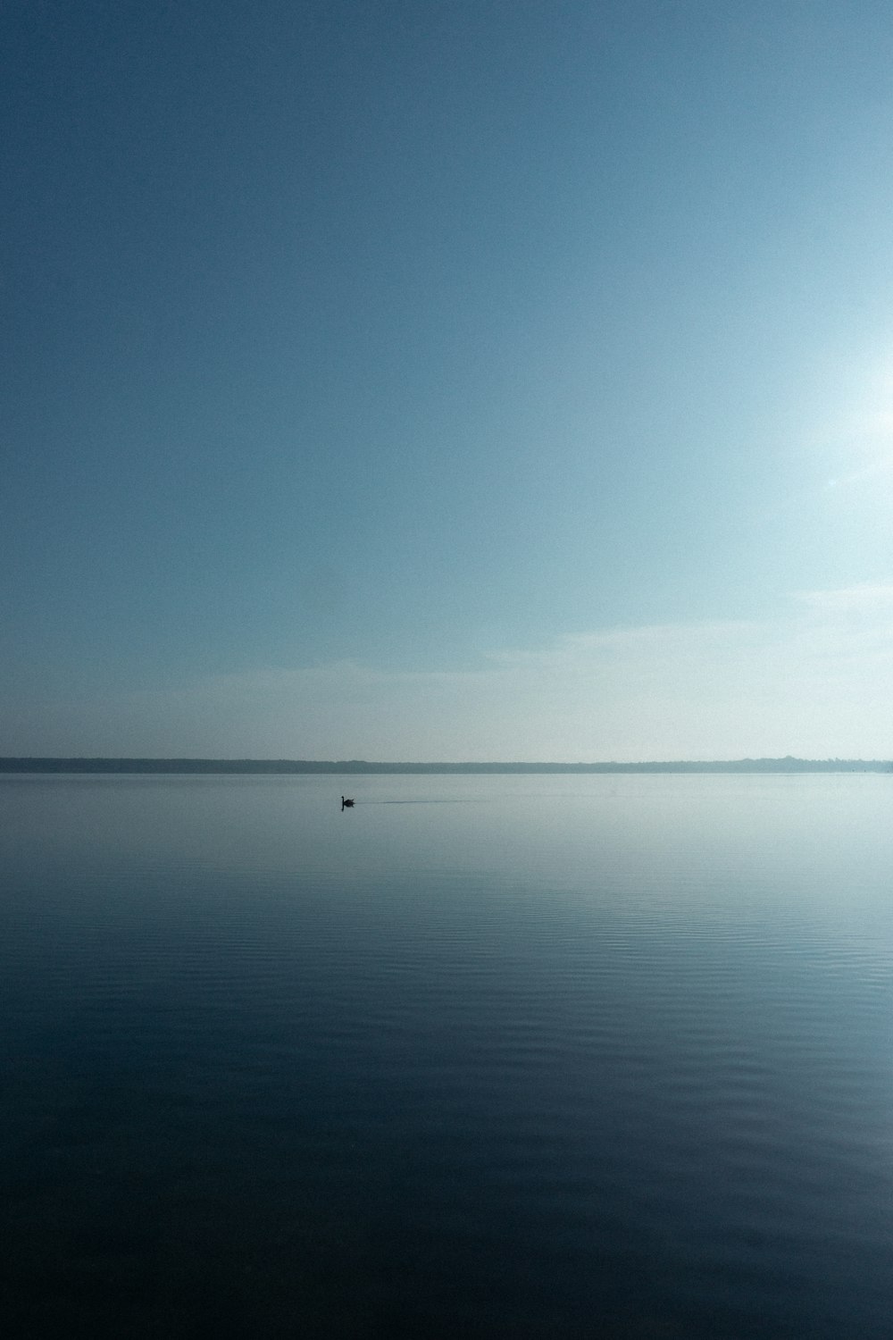 a large body of water sitting under a blue sky