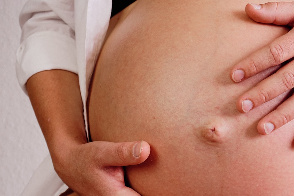 a close up of a person touching a pregnant belly