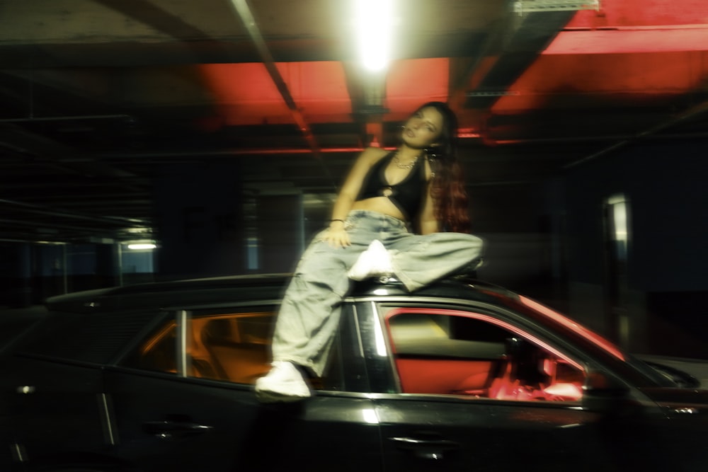 a woman sitting on top of a car in a parking garage
