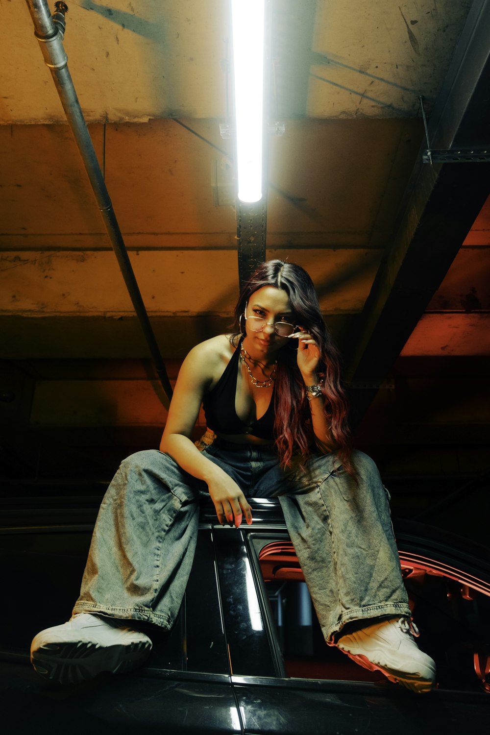 a woman sitting on top of a car talking on a cell phone