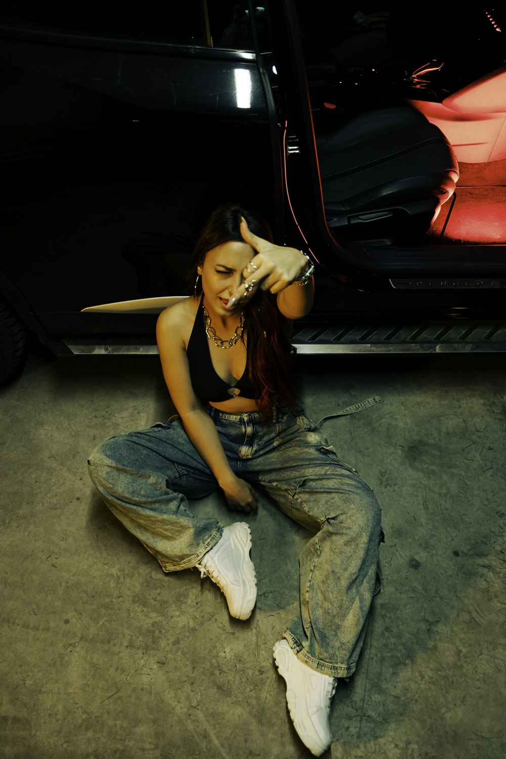 a woman sitting on the ground next to a car