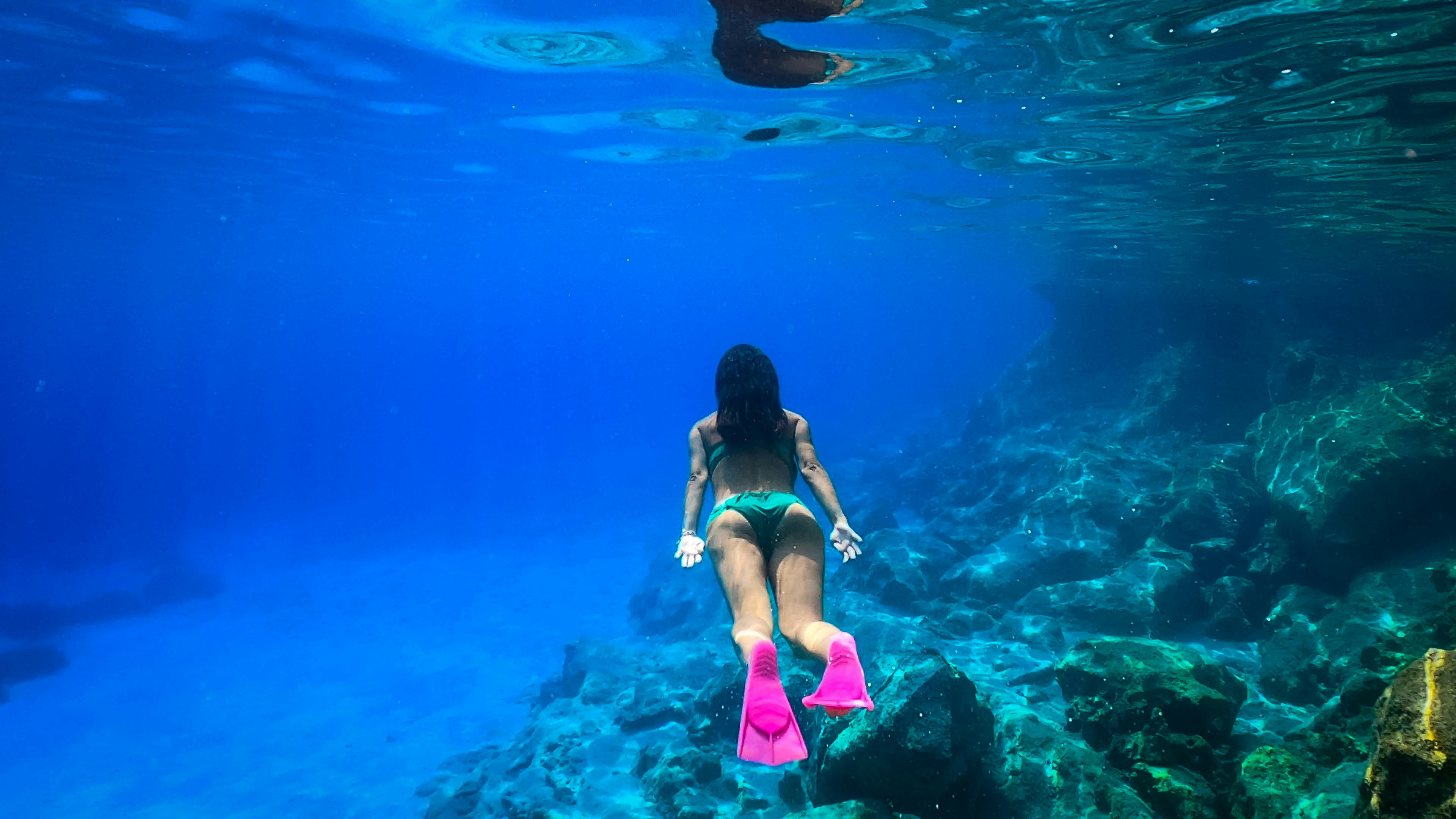 a woman in a bikini swims under water