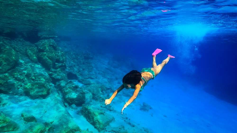 a woman swimming in the ocean with a pink frisbee