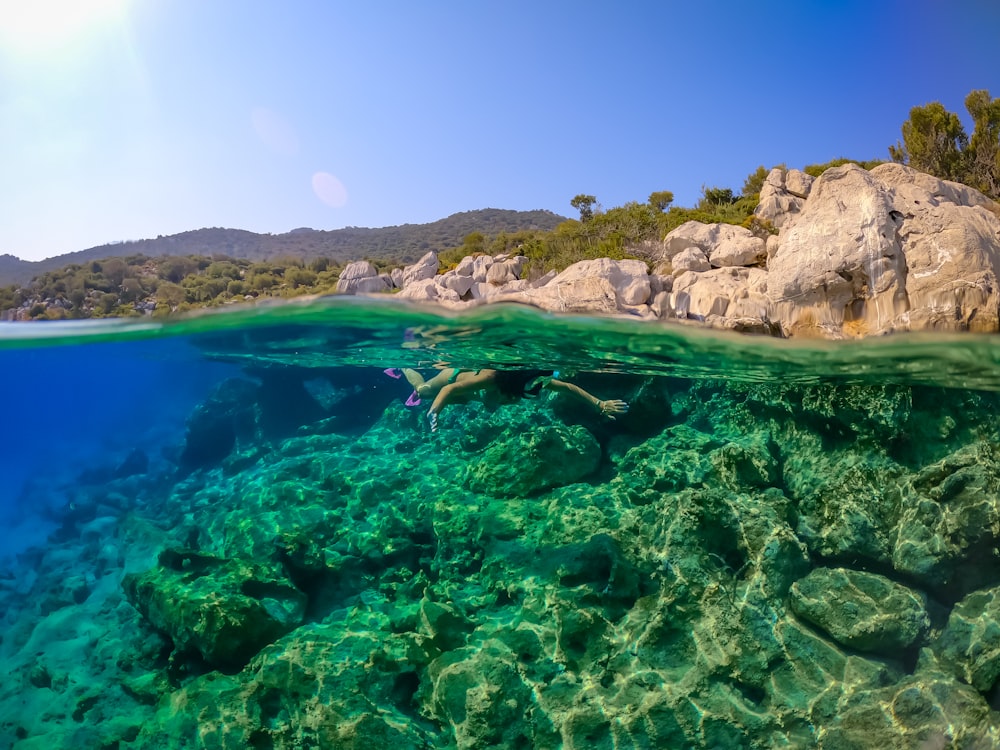 a person swimming in the water near some rocks