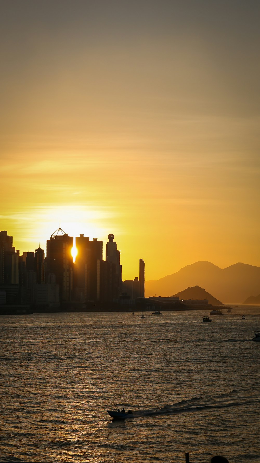 the sun is setting over a city on the water